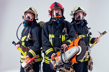 Portrait of three firefighters standing together white background studio