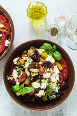 Italian traditional Tuscan panzanella salad with fresh tomatoes and cheese in clay plates and white wine in a bottle and glasses . authentic Mediterranean healthy food