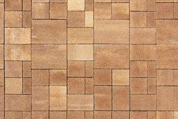 The surface is paved with road tiles of different sizes (multiformat). The uneven (melange) color of the tile makes it look like a natural stone. View from above.