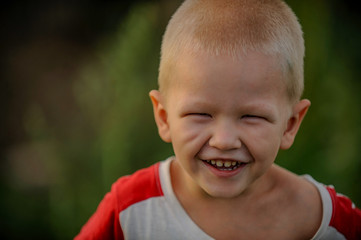 Rustic boy in T-shirt play in farmyard on background of sunset. child is happy in village on vacation