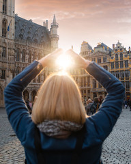 Woman stands in the square Grand Place in Brussels, Belgium at sunset.
