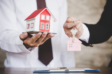 Real estate agent with house model and keys.