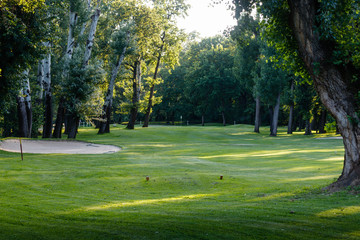 Green grass on the empty golf course, sand pit on the golf course