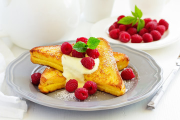 French toast with english sauce and raspberries.