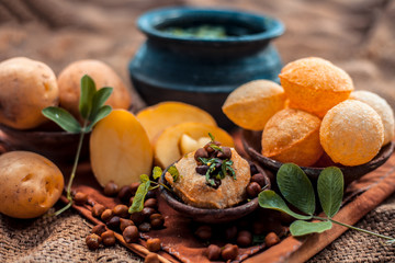 Famous Indian & Asian street food dish i.e. Panipuri snack in a clay bowl along with its flavored...