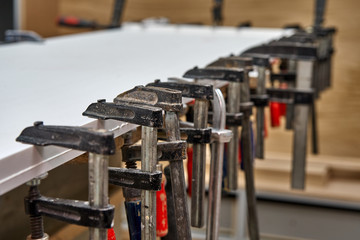 Gluing and clamping table top of acrylic stone. Production of wood furniture. Furniture manufacture. Close-up
