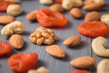 Granola cereal flakes with dried fruit, nuts in green bowl on gray wooden table.