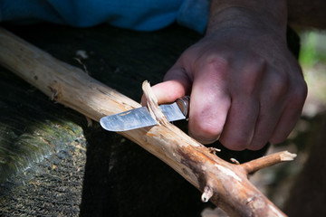 Man creating a walking stick with a knife