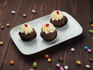 Cupcakes with whipped cream on brown wooden table