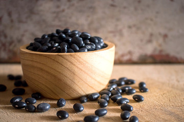 Black beans in wooden bowl set on cutting board.