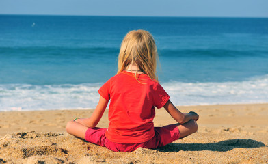 Fototapeta na wymiar Kid sitting at the sea on sand beach