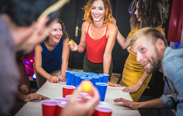 Young friends playing beer pong at youth hostel - Free time travel concept with backpackers having...