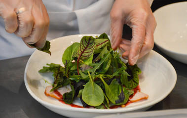chef prepares salad from ham and leaf lettuce