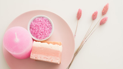 Spa therapy. Organic body care products. Top view of handmade soap, bath salt, candle and herbs on white background.