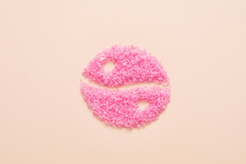 Beauty and health balance. Top view of pink bath salt crystals shaped in yin yang symbol over peach background. Copy space.