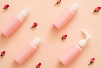 Rose essential oil natural cosmetic products. Travel kit mockup plastic bottles. Floral pattern peach background.