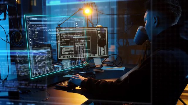 cybercrime, hacking and technology concept - asian male hacker in dark room writing code or using computer virus program for cyber attack