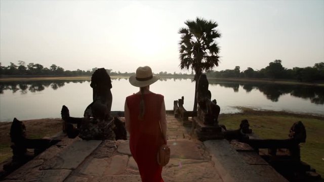 Slow motion: following woman walking to enjoy sunrise at the bank of Srah Srang, a baray or reservoir dug in the mid-10th century by khmer civilization. Angkor Wat, Cambodia