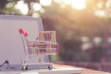 Shopping online concept - Parcel or Paper cartons with a shopping cart logo in a trolley on a...