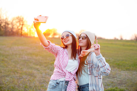 Two young women shooting autoportrait outdoors at sunset