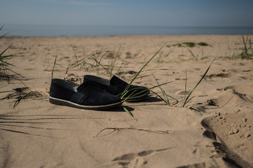 Fototapeta na wymiar Women's shoes on the sand of the beach. Sandy beach at a resort in Estonia. Narva Bay Narva-Joessuu. Sunny day, summer.