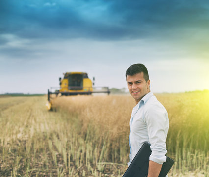 Businessman with laptop in front of combine harvester
