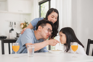 Asian family happy enjoy having breakfast on table in kitchen