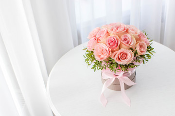 Beautiful bouquet of pink roses in a festive round box on a white table. Gift for holiday, birthday, Wedding, Mother's Day, Valentine's day, Women's Day.  Flowers in a hat box.