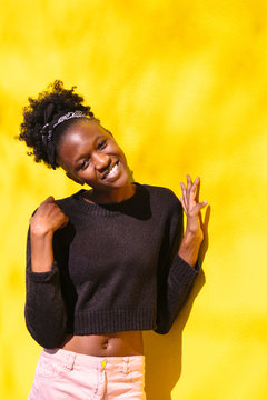 Young african girl stands half-turned near wall