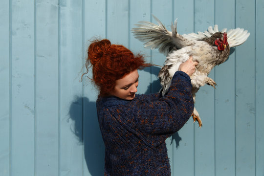 Rural woman holding chicken waving wings