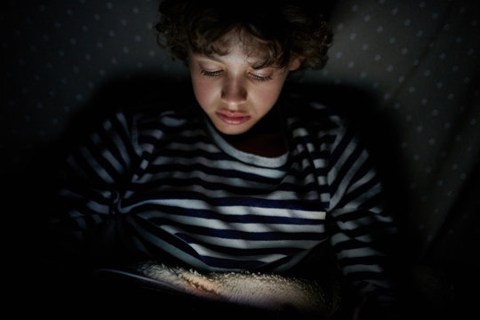 Little boy enjoying tablet in darkness