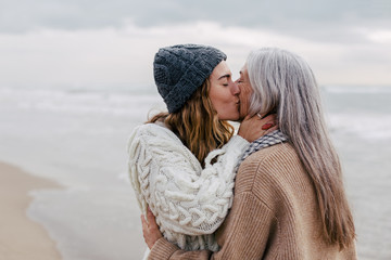 Daughter kissing her mother on the beach.