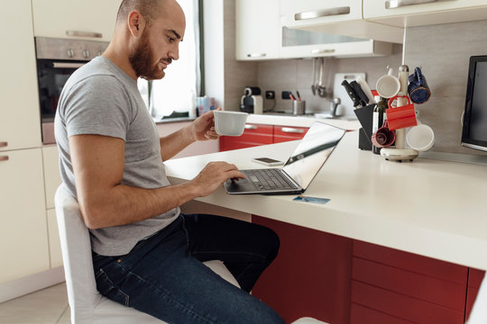 Adult Couple Using a Laptop From a Kitchen during the Morning Breakfast