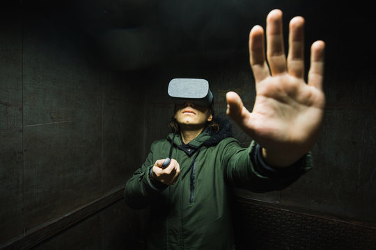 Young man using gray VR goggles finding himself in an industrial elevator