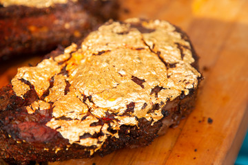 A medium rare tomahawk steak covered with a layer of gold