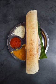 Indian dosa on a platter with sambar chutnies