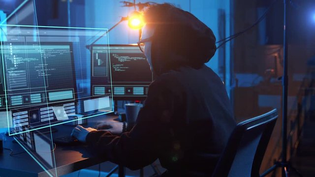 cybercrime, hacking and technology concept - asian male hacker in dark room writing code or using computer virus program for cyber attack