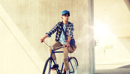 people, style, leisure and lifestyle - young hipster man with shoulder bag riding fixed gear bike...