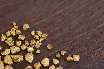 mound of gold nugget on dark wood background