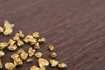 mound of gold nugget on dark wood background