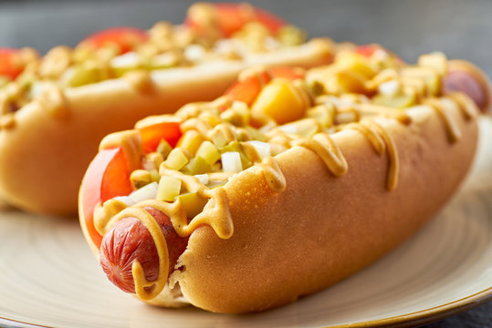 Two juicy hot dogs close-up on dish over stone table