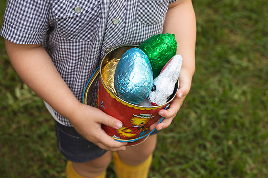A young toddler boy has a chocolate easter egg hunt in his backyard in Australia