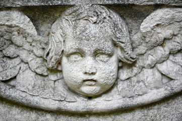 The weathered face of an angel. A damaged sandstone sculpture.