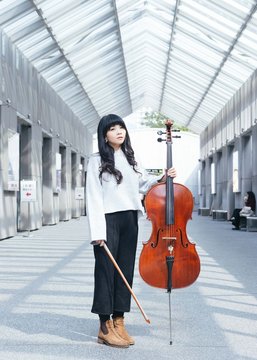 Portraits of female jazz cellist playing in outdoor space