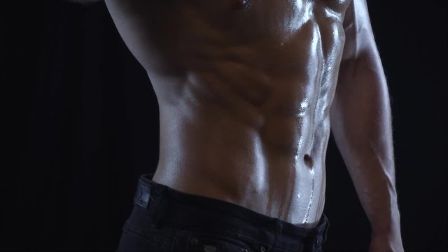 Young fit guy posing, showing abdominal side muscles, slow motion