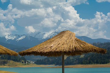 Thatch sun umbrella on sea and mountain background. A straw beach umbrella on the background of the...