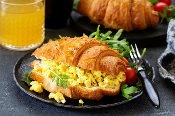 Breakfast of croissant with scrambled eggs and salad.