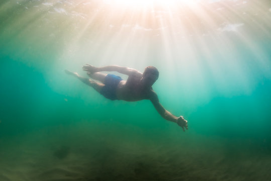 Man explores marine world in sunlight dappled murky water