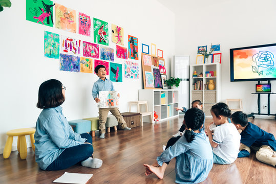 Preshool kid showing drawing to class