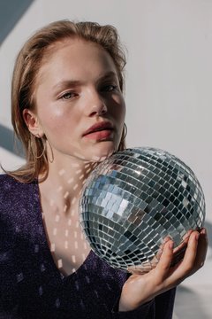 Amazing blond girl posing indoors with disco ball and looking at camera